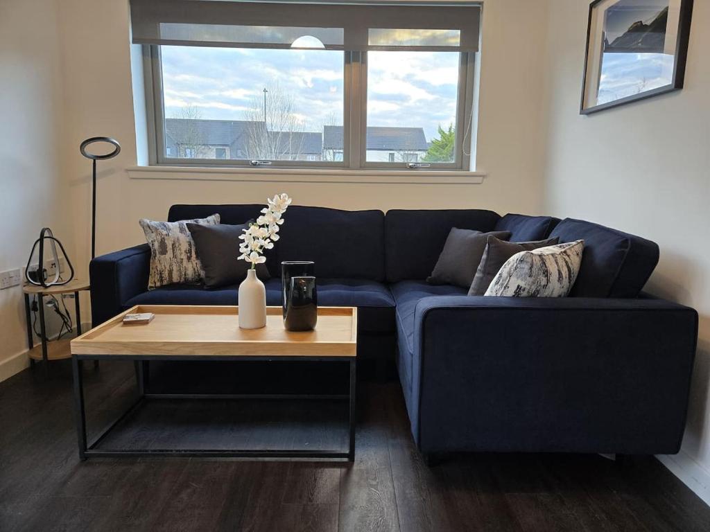 een blauwe bank in een woonkamer met een tafel bij Modern Stirling Apartment - Free Parking in Stirling