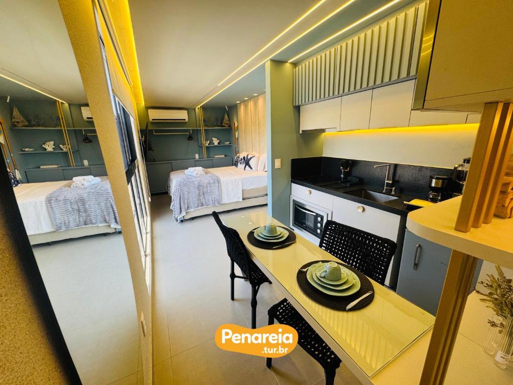 a kitchen with a table and two beds at Emunah Di Città Flats Ponta de Campina in Cabedelo