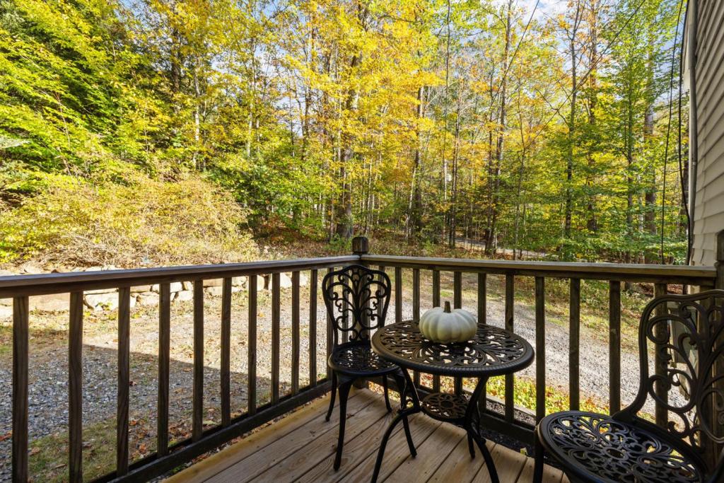 a porch with two chairs and a table with a pumpkin at Hiking, Lakes & Cozy Evenings in the Pines in Gilmanton