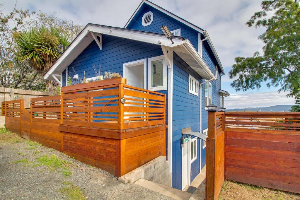 une maison bleue avec une clôture en bois devant elle dans l'établissement 1 Mi to Dtwn Coos Bay Sleek Apt with Deck and Views!, à Coos Bay