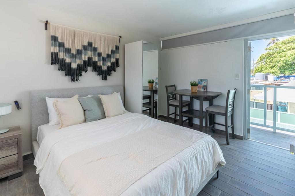 a bedroom with a large white bed and a table at AQUA Terrazas Studio 5 - Oceanfront, Pool & Local Dining in Mameyal