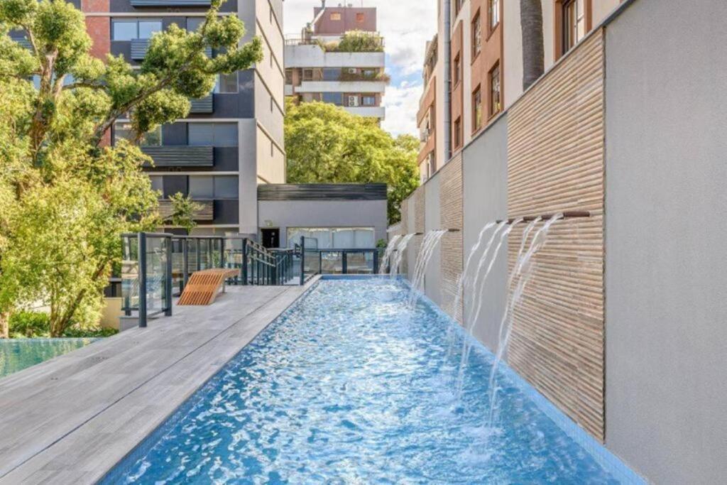 a swimming pool with a water fountain on a building at Studio Lucas By Yoo Luxo in Porto Alegre