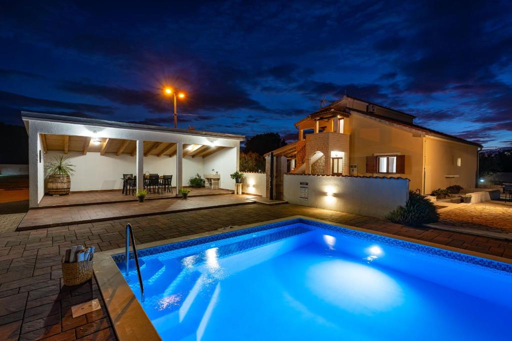 a swimming pool in front of a house at night at My Dalmatia - Villa Marijana in Radonić