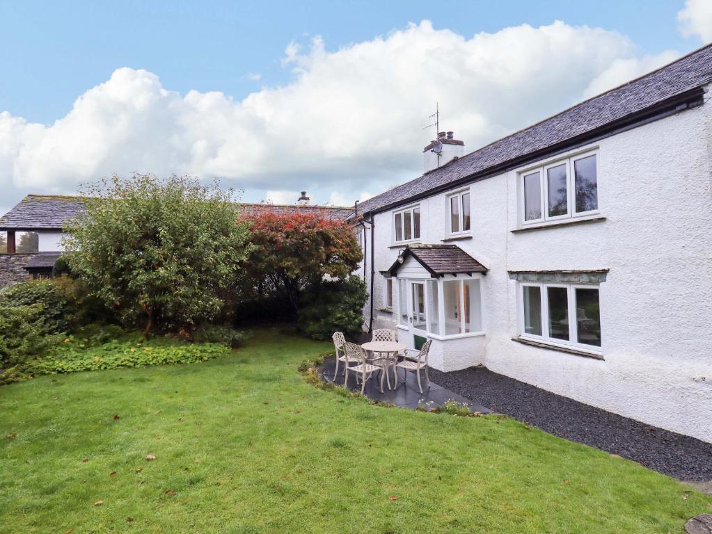 a white house with a yard with a table and chairs at Ecclerigg Old Farm in Ambleside