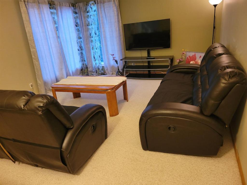 - un salon avec 2 fauteuils en cuir et une télévision à écran plat dans l'établissement Master bedroom in a quiet and smoke-free home, à Winnipeg