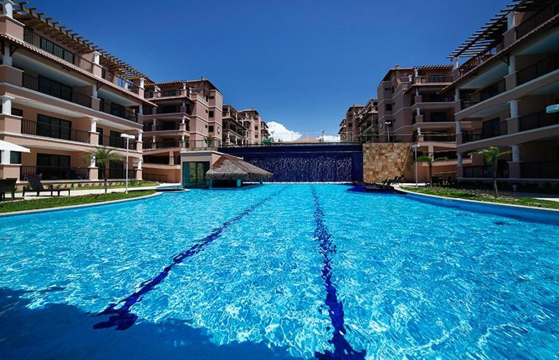 une grande piscine d'eau bleue devant les bâtiments dans l'établissement Beverlly Hills, à Aquiraz