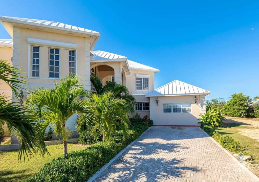 ein großes weißes Haus mit Palmen davor in der Unterkunft Breathtaking Chalk Sound Private Pool Sunset Villa in Providenciales