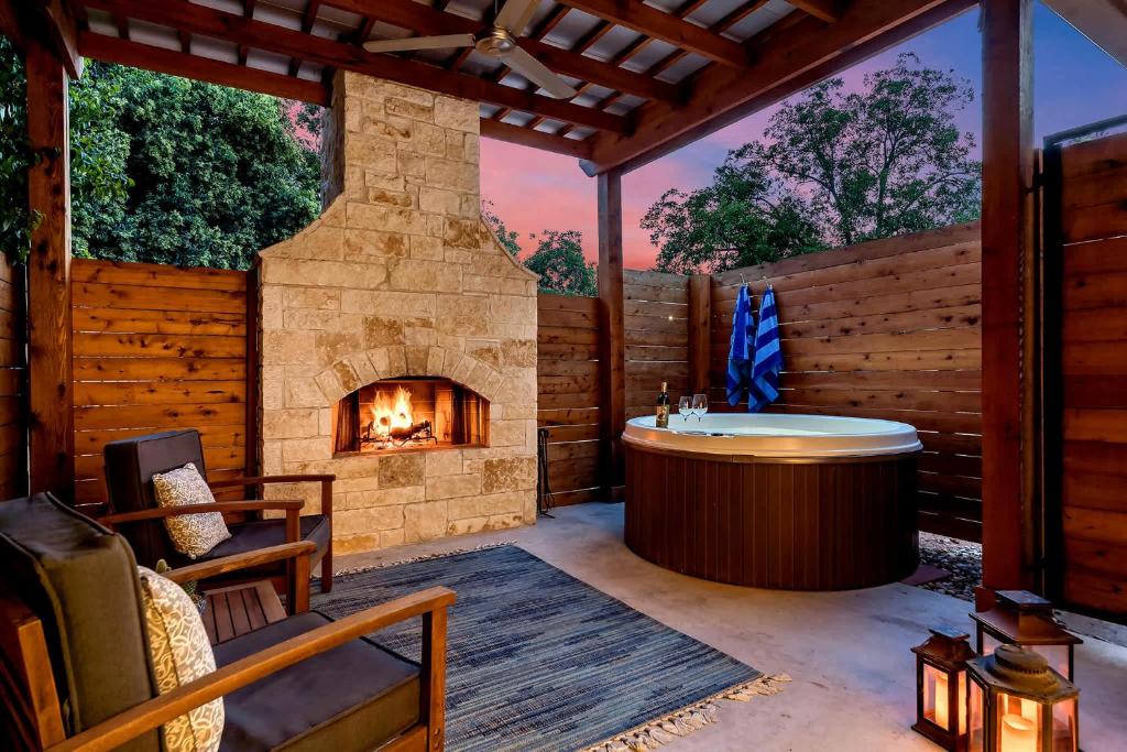 a patio with a fireplace and a hot tub and a fireplace at An Enchanted Hideaway outdoor fireplace hot tub in Fredericksburg