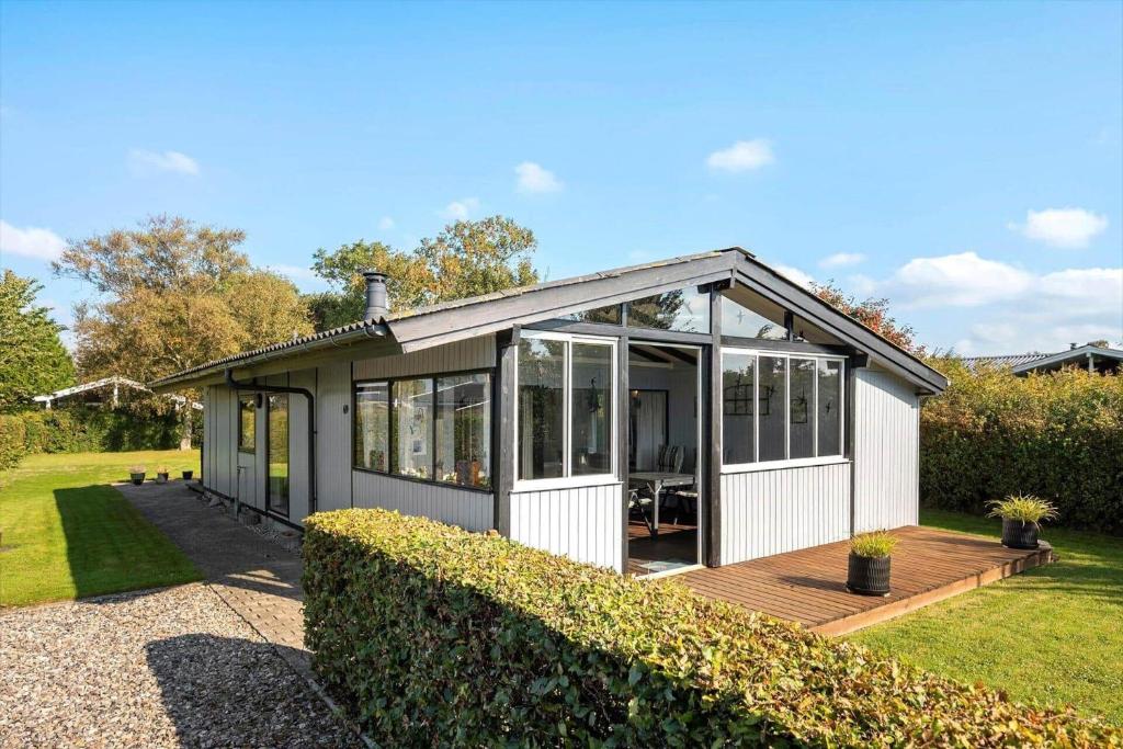 une petite maison avec une terrasse dans une cour dans l'établissement N336-Karrebaeksminde-Cypresvaenget-69, à Enø By