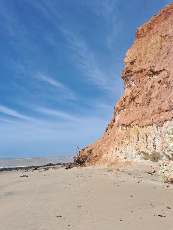 a sandy beach with a cliff and the ocean at Falésias de Marataizes in Marataizes
