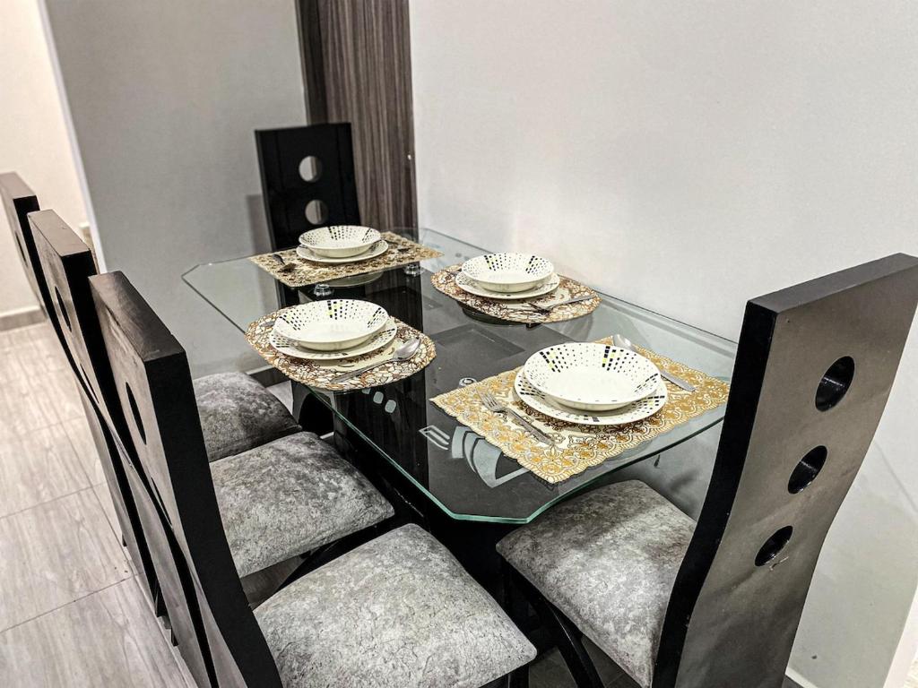 a glass dining table with chairs and plates on it at The house of your dreams located in Pitalito! in Pitalito
