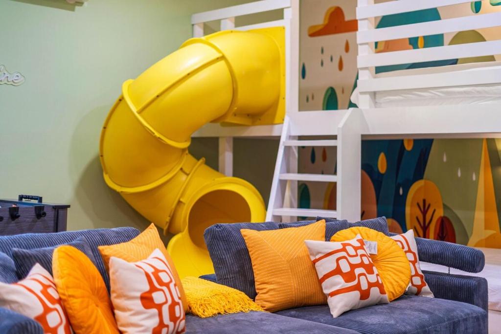 a room with a blue couch with orange pillows and a slide at Pet Friendly, Mini Golf, Game Room, Hot Tub in McGaheysville