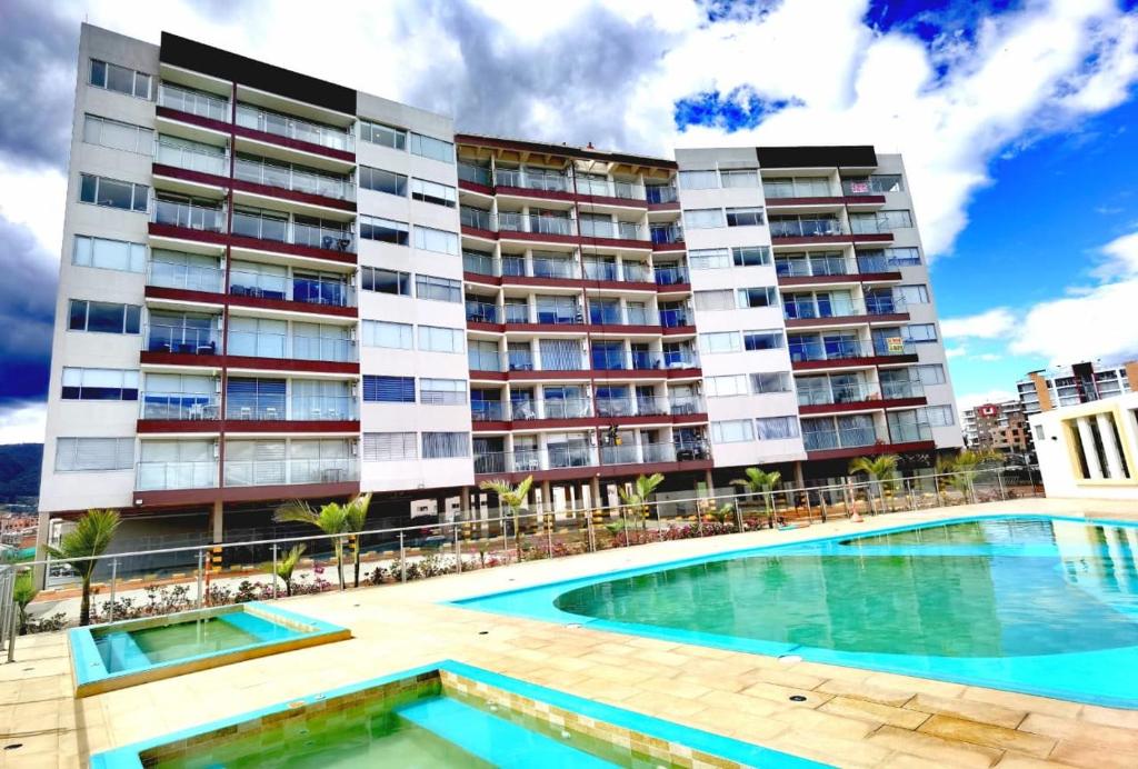 a building with a swimming pool in front of a building at Exclusivo apartamento con vista al lago Sochagota in Paipa