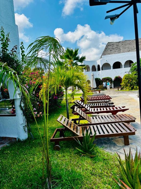 a row of wooden lounge chairs in a yard at Jean pierre studio apartment in Malindi