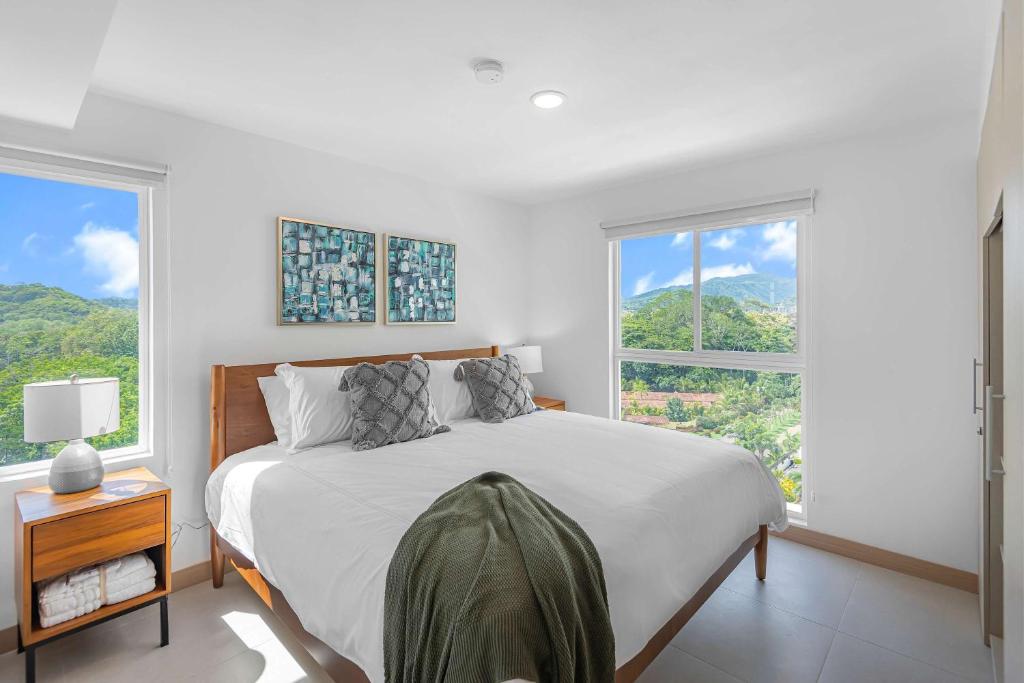 a white bedroom with a large bed and two windows at Upstay Brand New 3BR Viva Jaco Residences in Jacó
