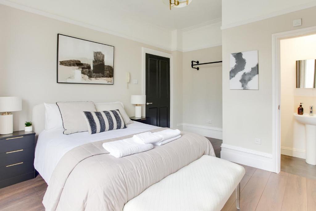 a white bedroom with a large bed and a bench at Luxiety Stays Brand New Ensuite Rooms Near Cambridge City Centre in Cambridge