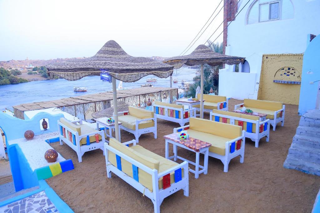 a group of chairs and tables on a patio with a river at Nubian Palace Eco Lodge in Aswan