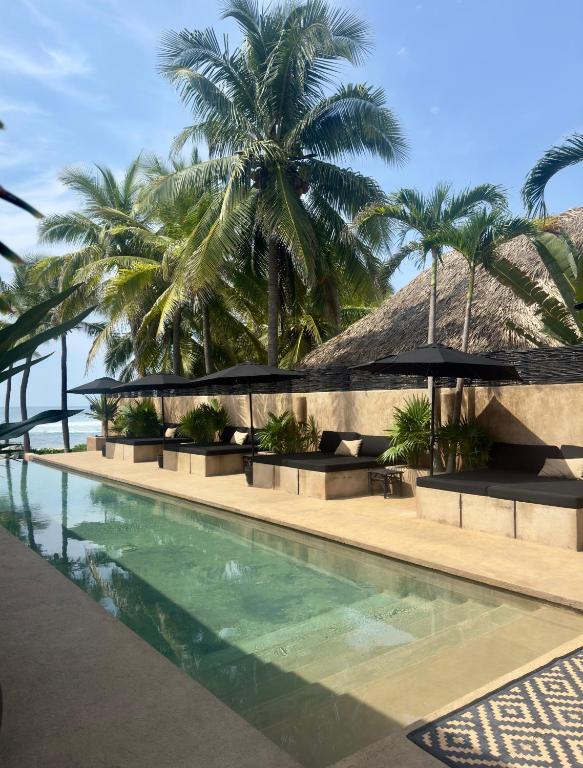 a resort swimming pool with palm trees in the background at The Casa Saint George Hotel in Troncones
