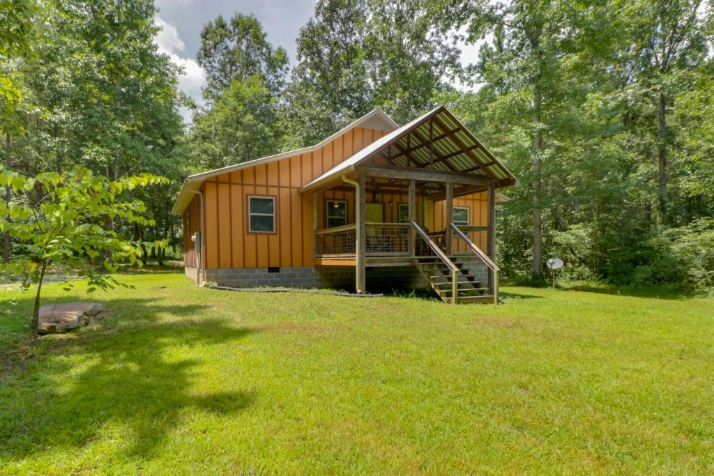 a small wooden cabin in a field of grass at Serene and Secluded Alabama Cabin with Covered Deck! in Fort Payne
