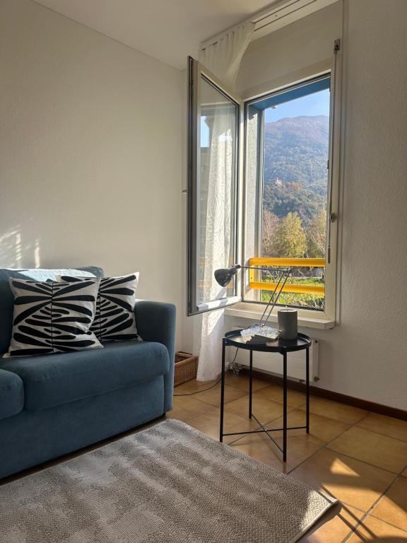 a living room with a blue couch and a large window at BelliCastelApartment in Bellinzona