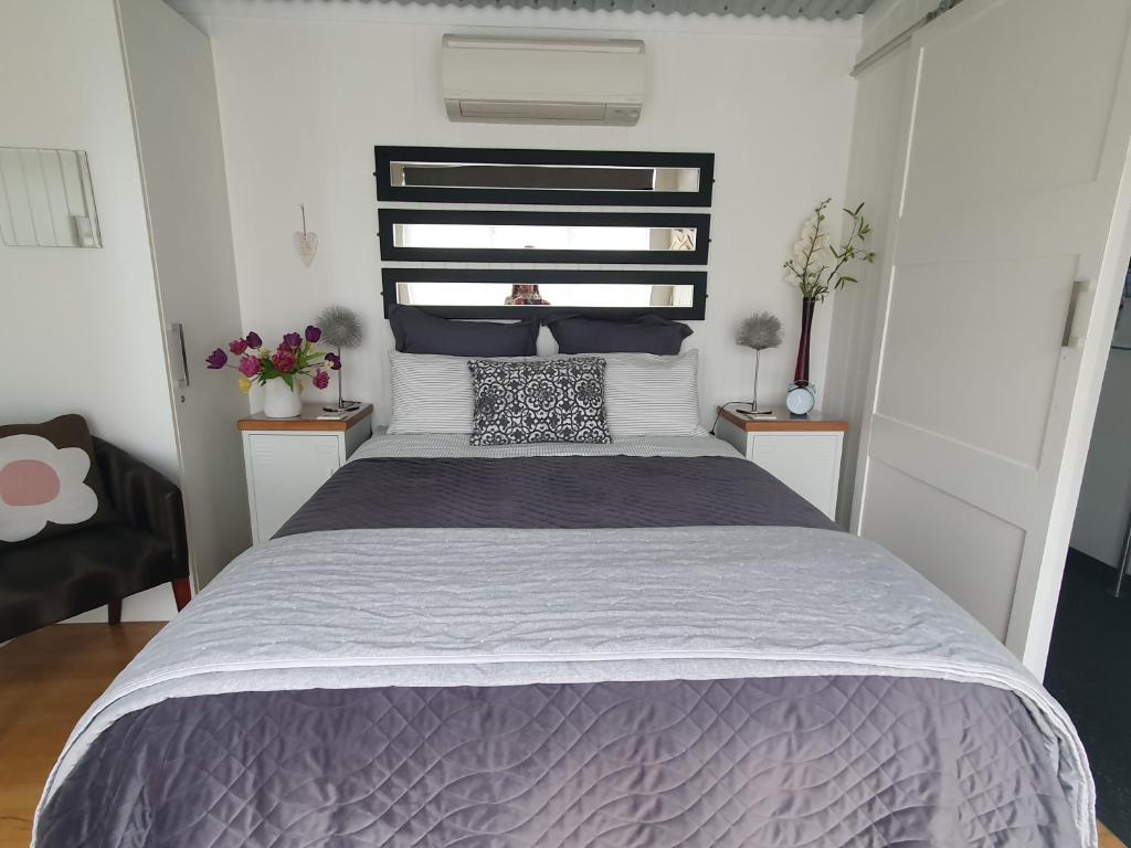 a bedroom with a bed and two tables with flowers at The Cube in Martinborough 
