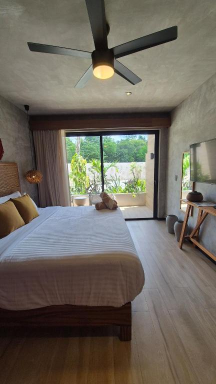 a bedroom with a large bed with a ceiling fan at Tuk Tulum Estudio con Balcon 005 in Tulum