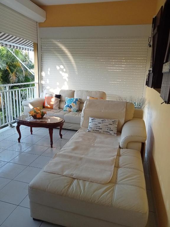 a living room with a white couch and a table at Villa Grandes pièces in Petit-Bourg
