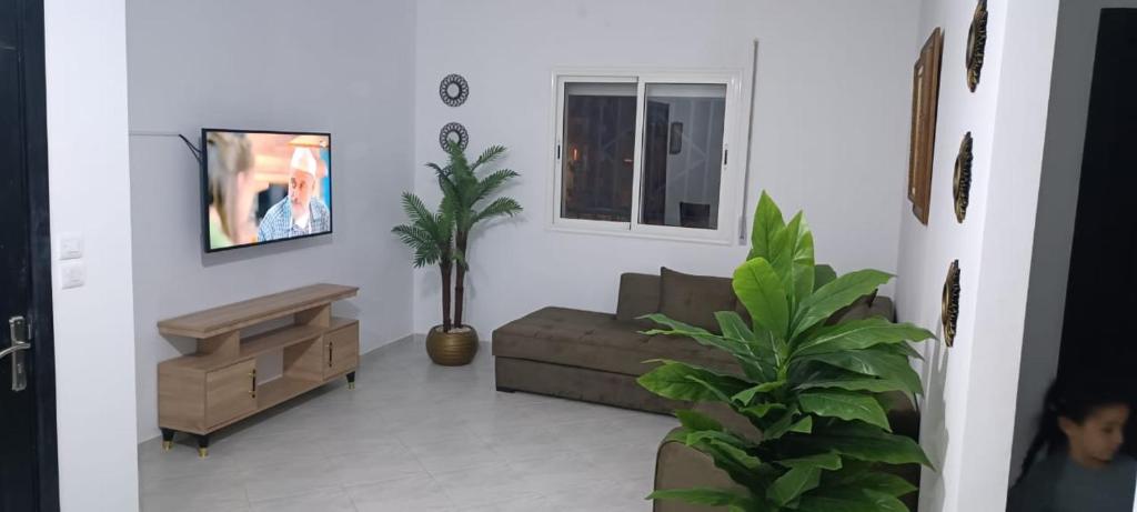 a living room with a couch and a tv at Maison de cèdre in Azrou