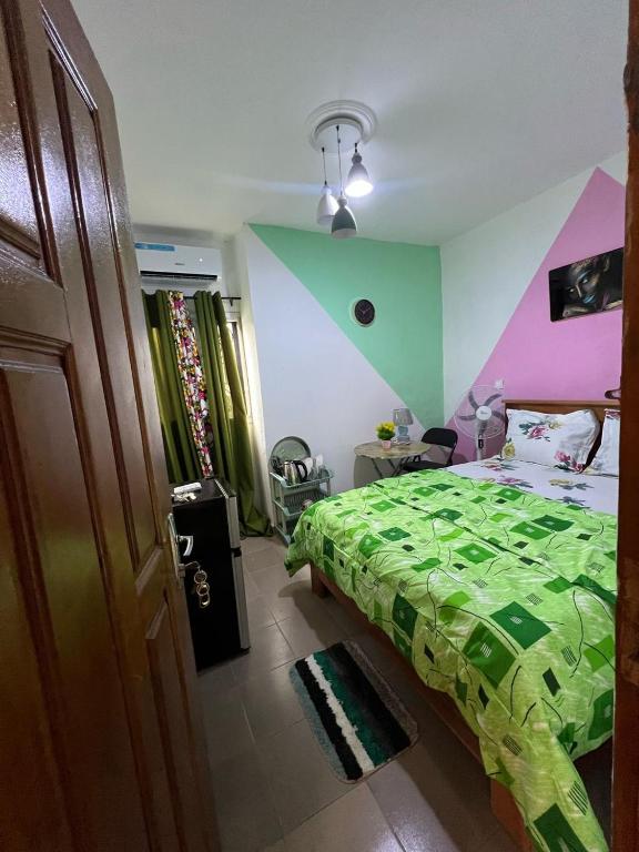 een slaapkamer met een bed met een groen dekbed bij Vision Hébergement in Bonabéri