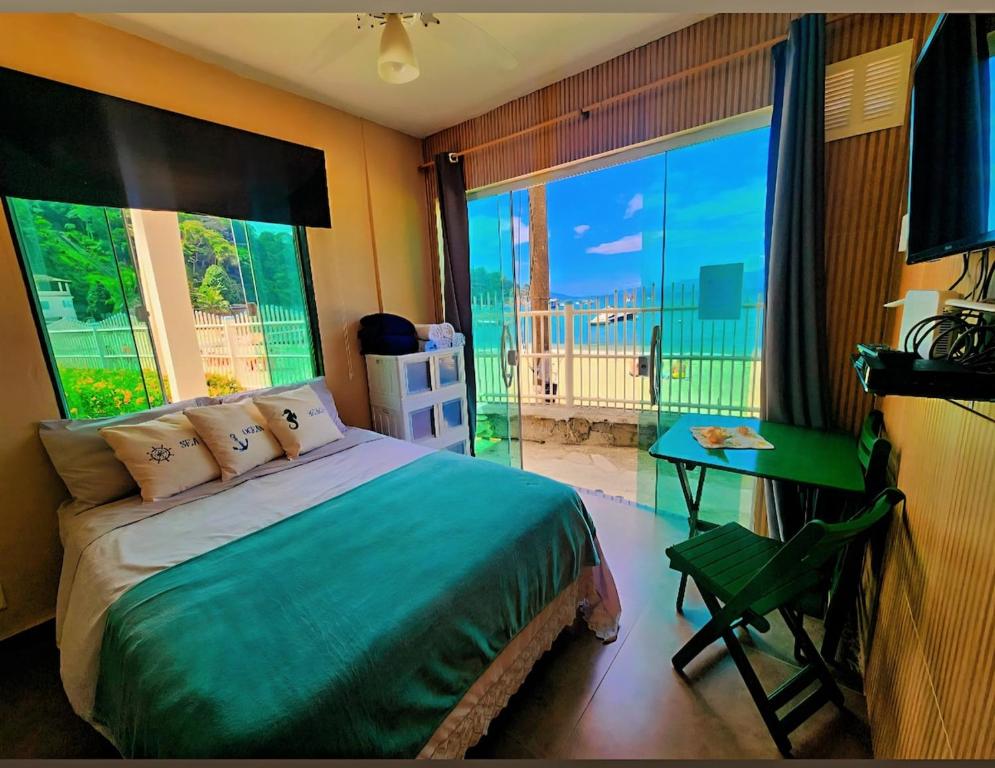 ein Schlafzimmer mit Bett, Schreibtisch und Fenster in der Unterkunft Ap bonfim Angra dos Reis, frente ao Mar in Angra dos Reis