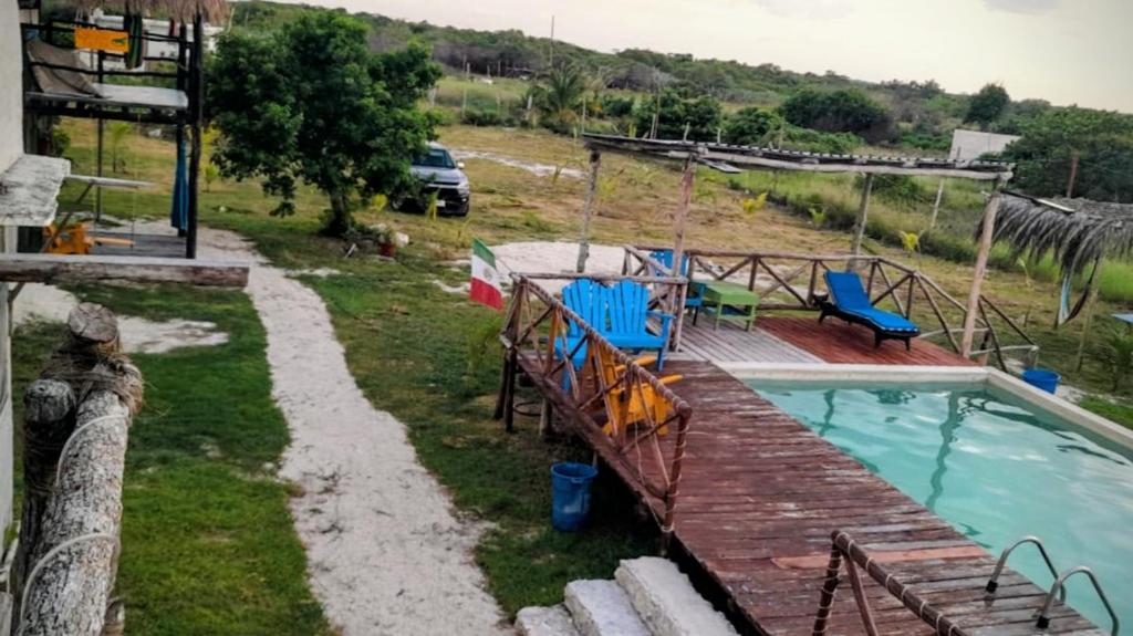 una piscina con terraza y sillas junto a una casa en Camping y Cabañas Chelem, en Chelem