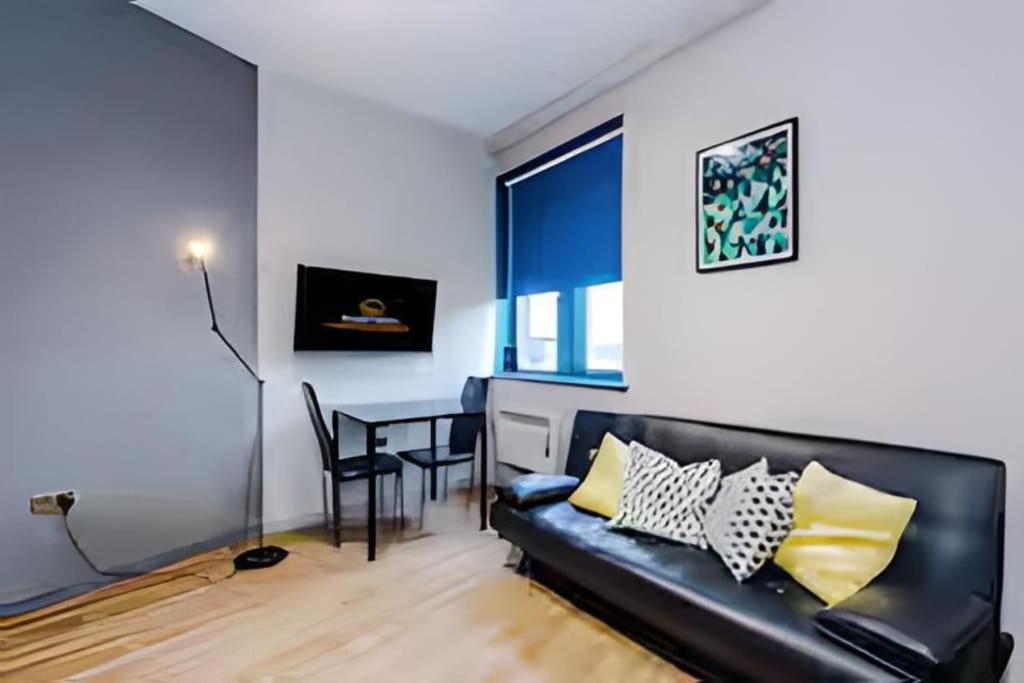 a living room with a black couch and a table at 1 BR Flat By Eason Stays Short Lets & Serviced Accommodation Wigan With Free parking! in Wigan