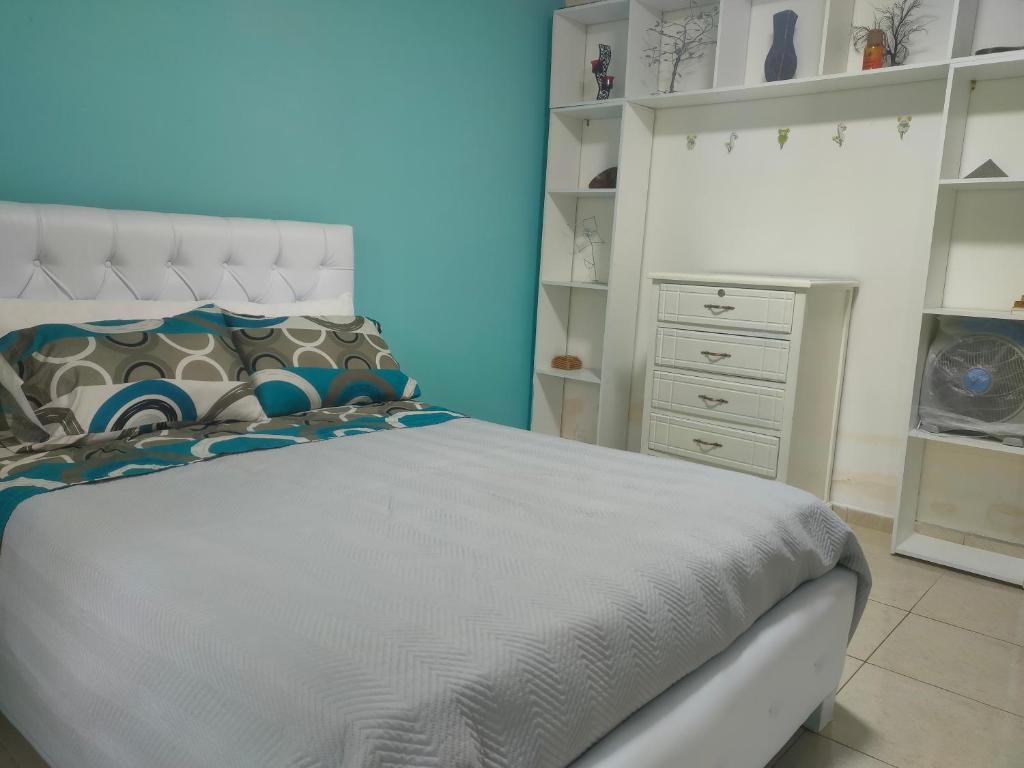 a bedroom with a white bed and a dresser at Habitación confort in Puyo