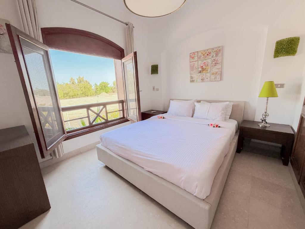 a bedroom with a bed and a large window at Nayah Stays, Cozy lagoons terrace one ensuite Apt in Hurghada