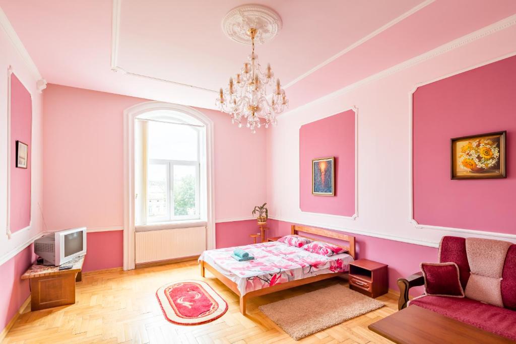 リヴィウにあるTwo Rooms Apart Prospekt Svobodyのピンクの壁のベッドルーム1室、ベッド1台、ソファが備わります。