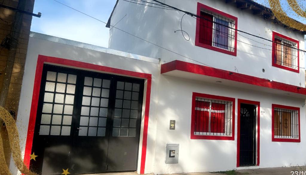 a white building with red windows and a door at 1-Monoambiente 