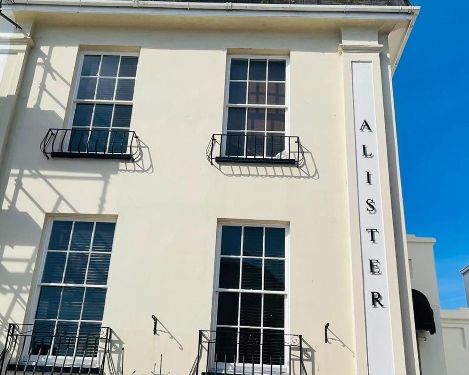 un bâtiment blanc avec une pancarte sur le côté dans l'établissement Alister Guest House, à Saint-Hélier