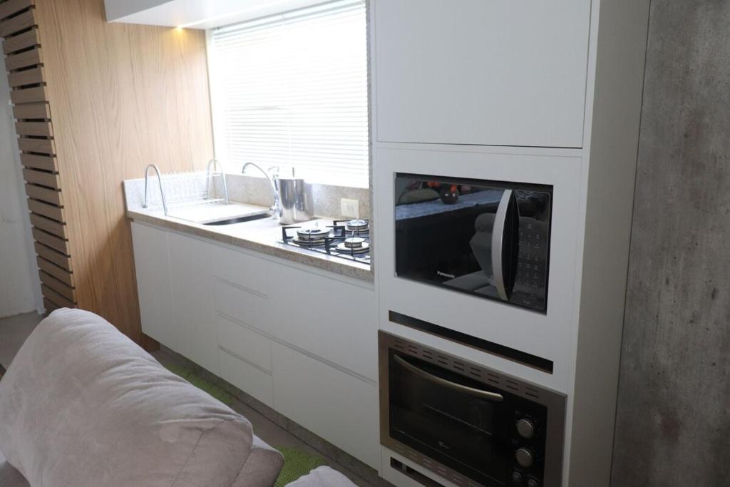 eine Küche mit Herd, Spüle und Mikrowelle in der Unterkunft São Bento Prime in São Bento do Sul