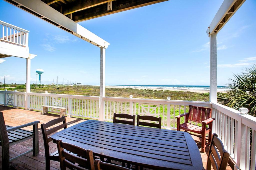 a table and chairs on a deck with the beach at Breakers Pointe in Galveston