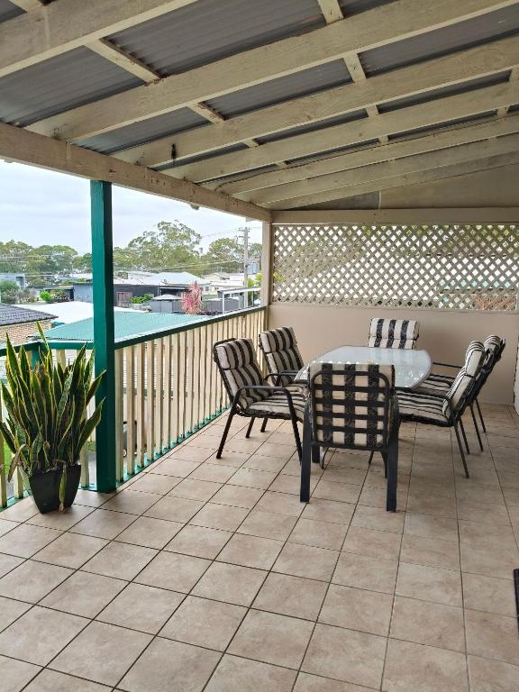 a patio with a table and chairs on a deck at Coconut Cottage by Book Jervis Bay - Sanctuary Point in Sanctuary Point