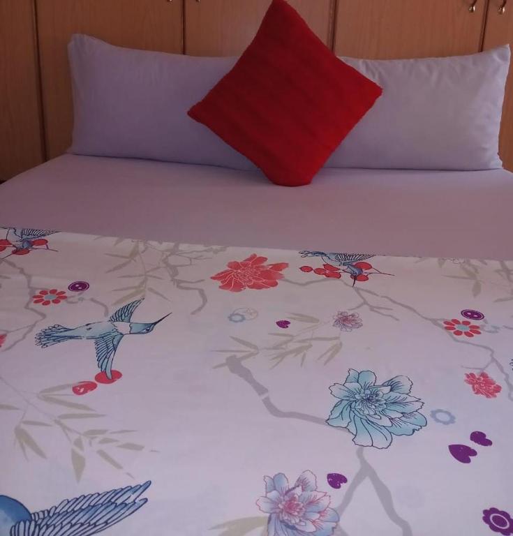 a bed with a bedspread with birds and flowers on it at Yana House in Polokwane