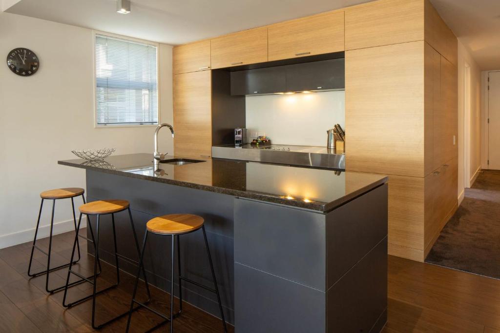 a kitchen with a counter and stools in a room at Lakeside Retreat Three Bedroom Apartment- 303 in Frankton Wharf