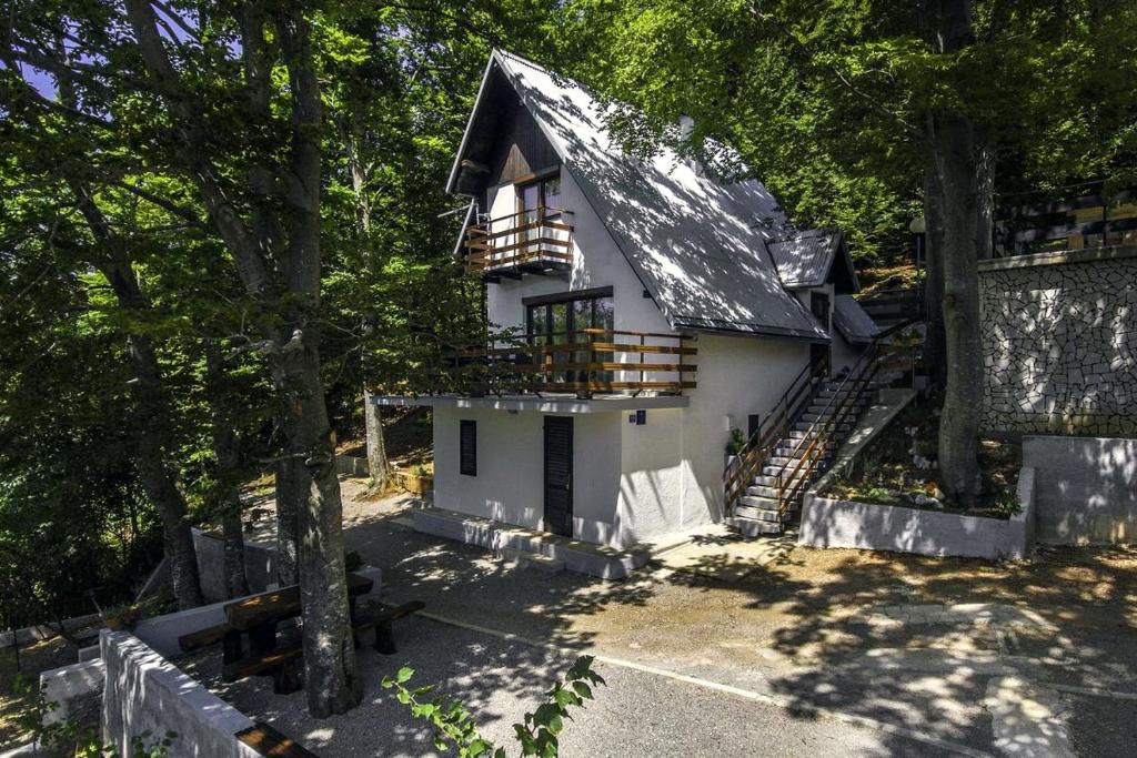 a white house with a black roof and some trees at Holiday house with a parking space Zlobin, Gorski kotar - 15452 in Benkovac Fužinski