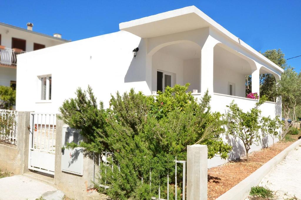 ein weißes Haus mit Bäumen davor in der Unterkunft Seaside holiday house Vinisce, Trogir - 16488 in Vinišće