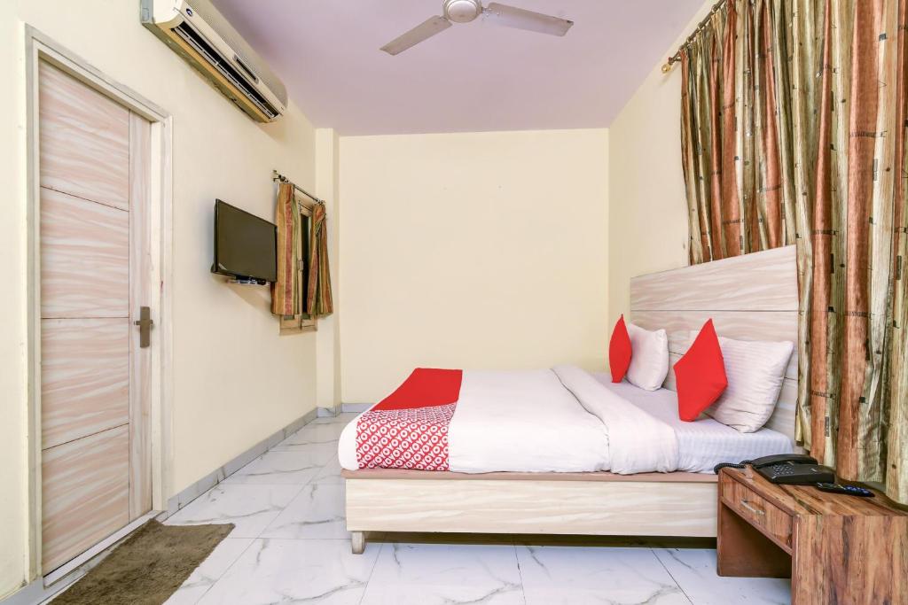 - une chambre avec un lit doté d'oreillers rouges et une télévision dans l'établissement Hotel O Vishwakarma Palace, à New Delhi