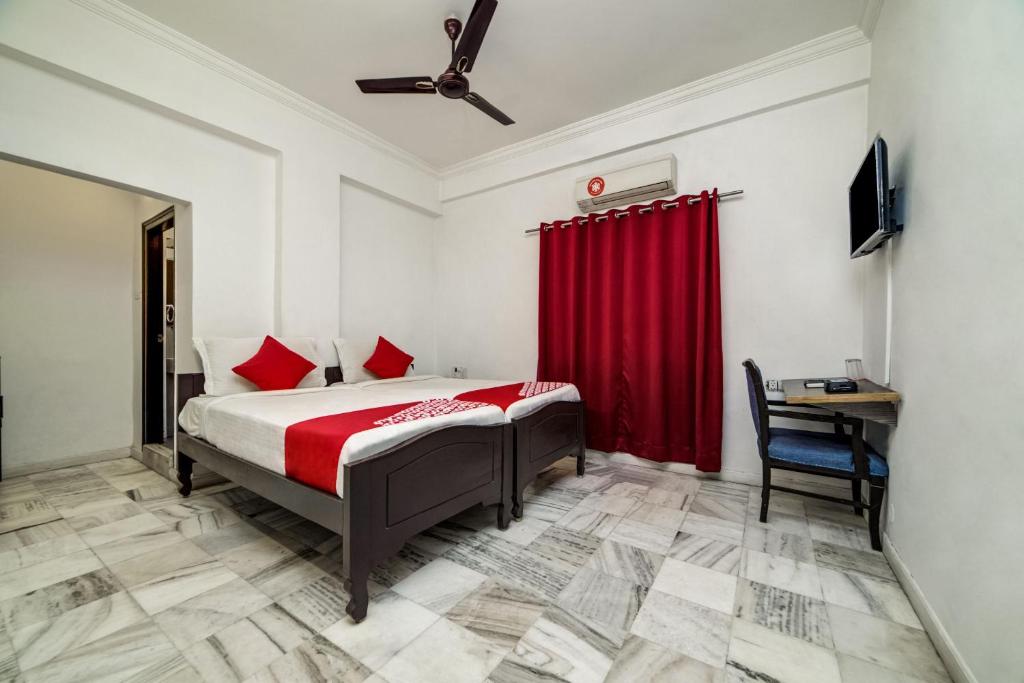 ハイデラバードにあるHotel O JNTU college Near LULU mall, KPHB Colony.のベッドルーム1室(赤いカーテン付きのベッド1台、デスク付)