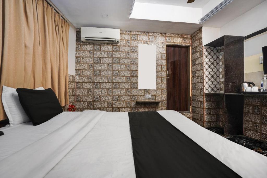 a bedroom with a large white bed and a brick wall at Hotel O Kanchan Palace in Ahmedabad