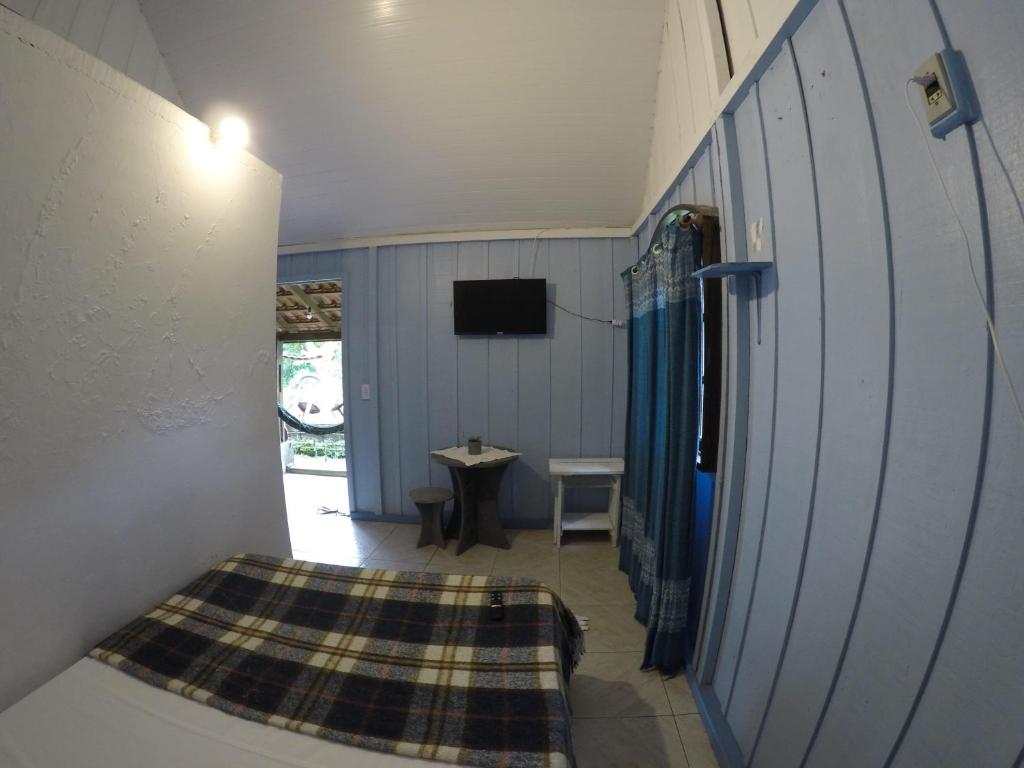 a room with a bed and a table and a television at Recanto Ana Valentin in Paranaguá