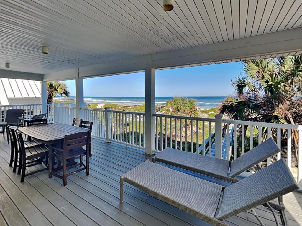 a porch with a table and chairs and the ocean at Four Palms in Saint Augustine