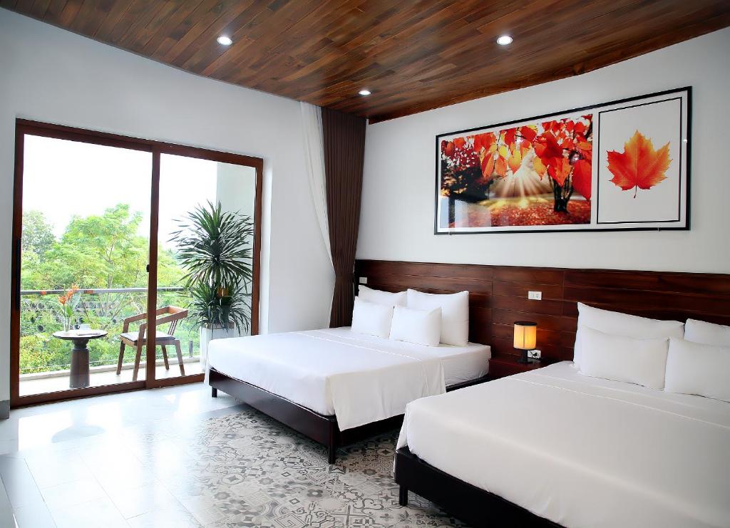 a bedroom with two beds and a large window at Daisy's Villa TamCoc in Vũ Lâm